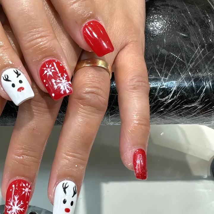 Christmas nails in glossy red with white snowflakes and reindeer faces