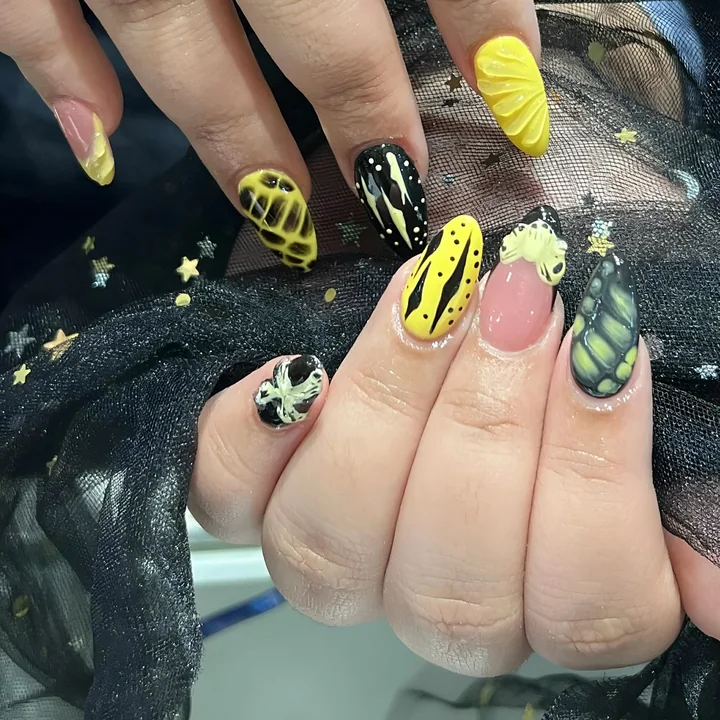 Yellow and black nail art with 3D shapes and lines