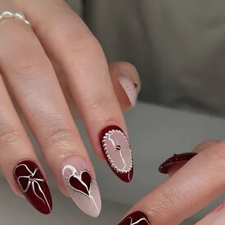 Wine red almond nails with a heart and bow design
